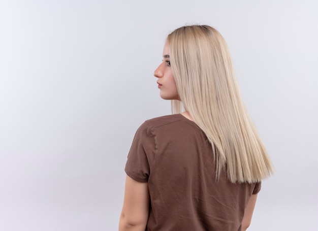 Free photo young blonde girl standing in behind view looking at left side on isolated white wall with copy space