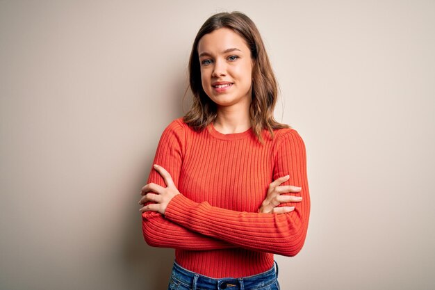 Young blonde girl wearing casual red sweater over isolated background happy face smiling with crossed arms looking at the camera Positive person