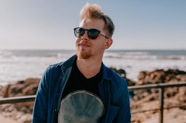Young blonde man with sunglasses on beach