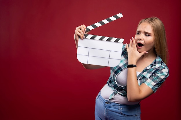 Free photo young blonde model holding a blank movie filming clapper board and looks dissatisfied.