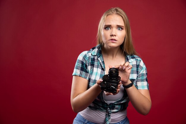 Young blonde photograph holding a professional camera and does not know how to use it. 
