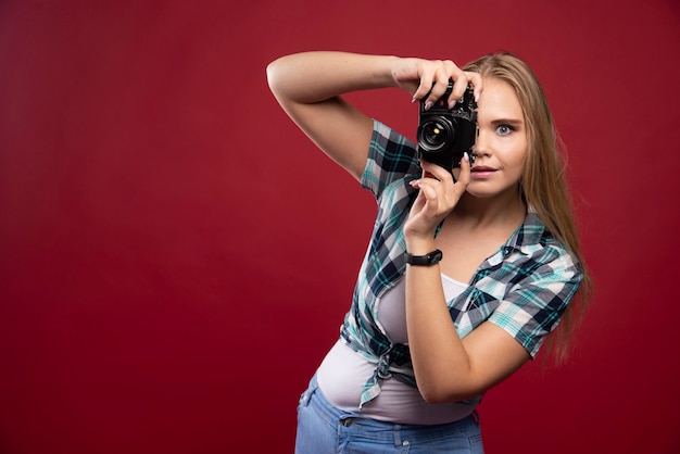 Foto gratuita giovane fotografia bionda in possesso di una macchina fotografica professionale e servizio fotografico in modo professionale.