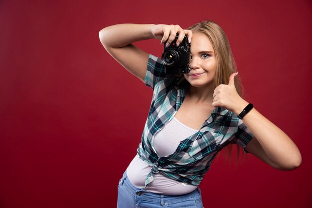 Young blonde photograph holding a professional camera and photoshooting in a professional manner.