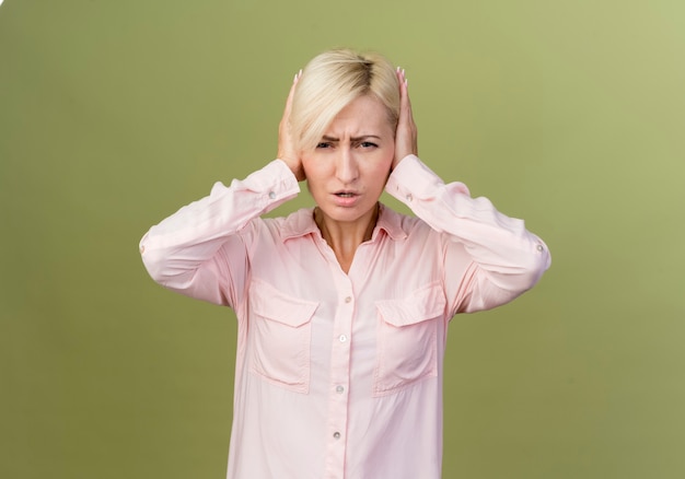 young blonde slavic woman covering her ears with hands