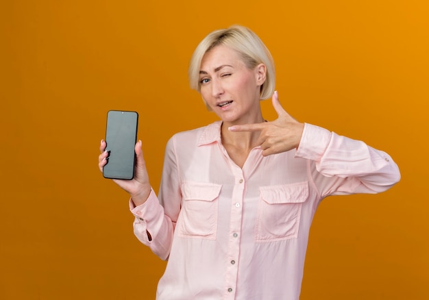 young blonde slavic woman holding and points at phone