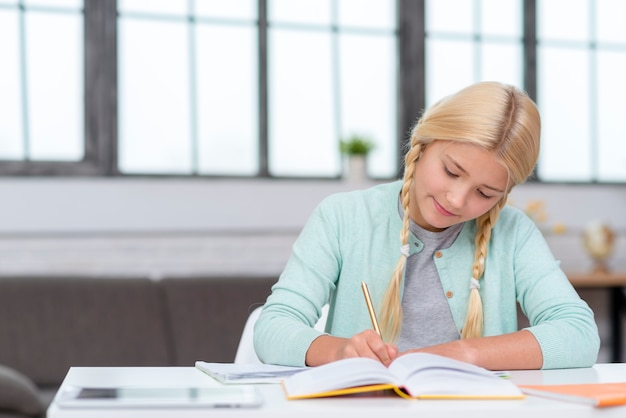 Foto gratuita giovane studentessa bionda che prende appunti dalla lezione