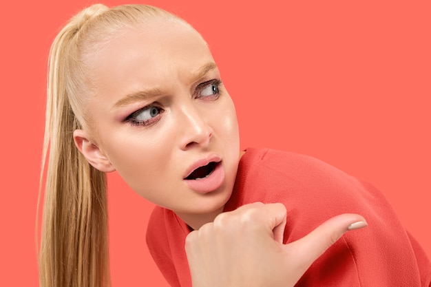 Free photo young blonde surprised woman on coral background