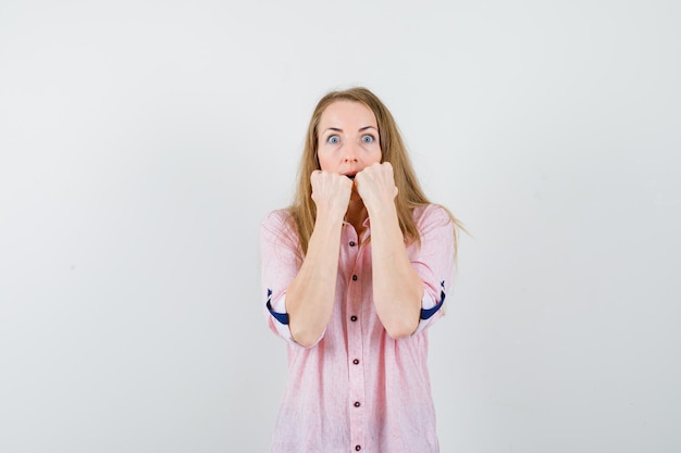 Young blonde woman in a casual pink shirt showing fists