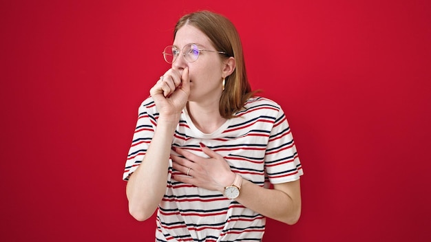 Foto gratuita giovane donna bionda che tossisce su uno sfondo rosso isolato