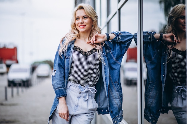 Free photo young blonde woman in a denim jacket outside