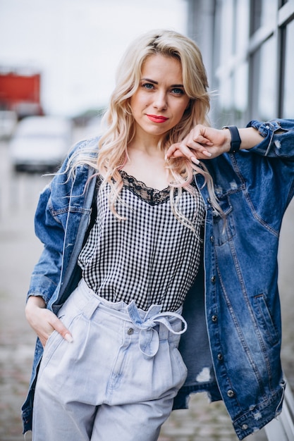 Young blonde woman in a denim jacket outside