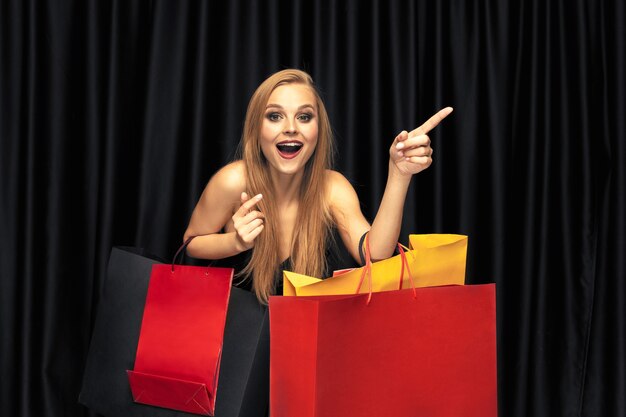 Young blonde woman in dress shopping on black wall