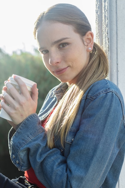 Young blonde woman drinking hot coffee