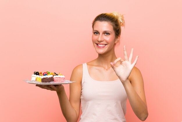 カップケーキを食べながらポーズ笑顔の若い女性 無料の写真