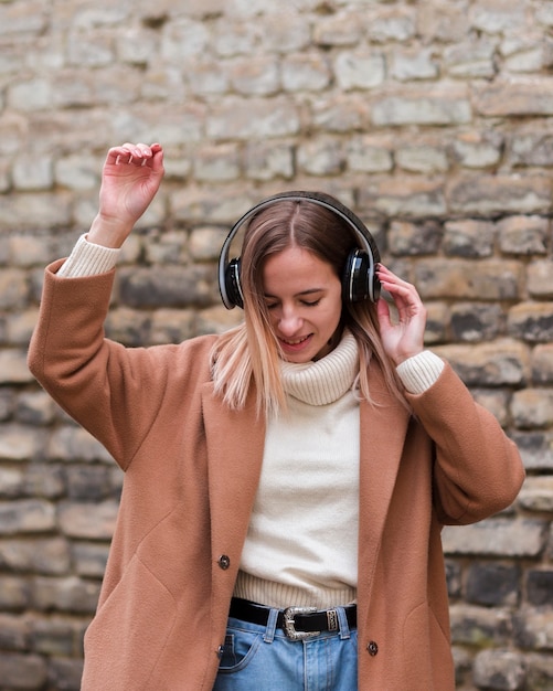 Бесплатное фото Молодая белокурая женщина слушая к музыке на наушниках снаружи