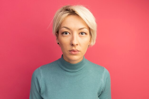 Young blonde woman looking at front isolated on pink wall