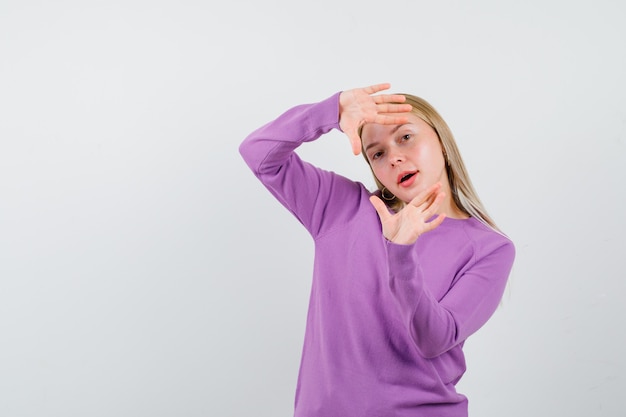 Giovane donna bionda con un maglione viola