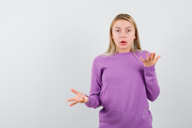 Foto gratuita giovane donna bionda con un maglione viola