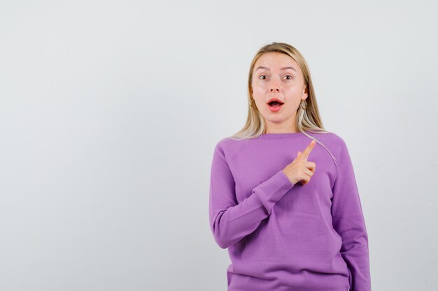 Giovane donna bionda con un maglione viola