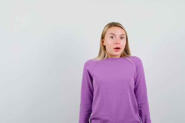 紫色のセーターを着た若いブロンドの女性