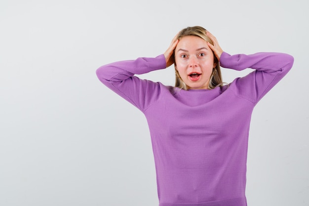 Giovane donna bionda con un maglione viola