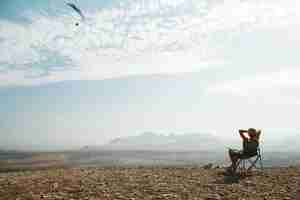 Free photo young blonde woman sitting on top of hill