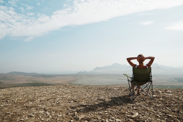 Young blonde woman sitting on top of hill