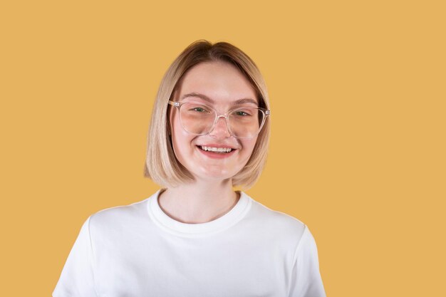 Young blonde woman smiling isolated on yellow