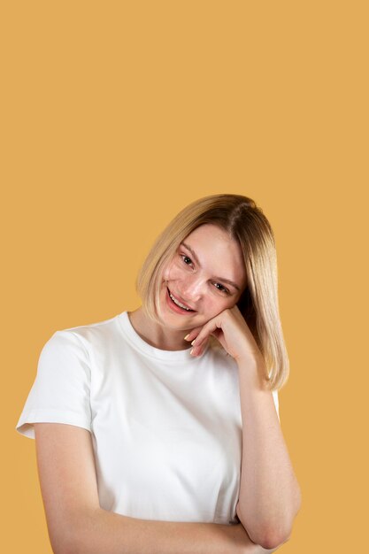 Young blonde woman smiling isolated on yellow