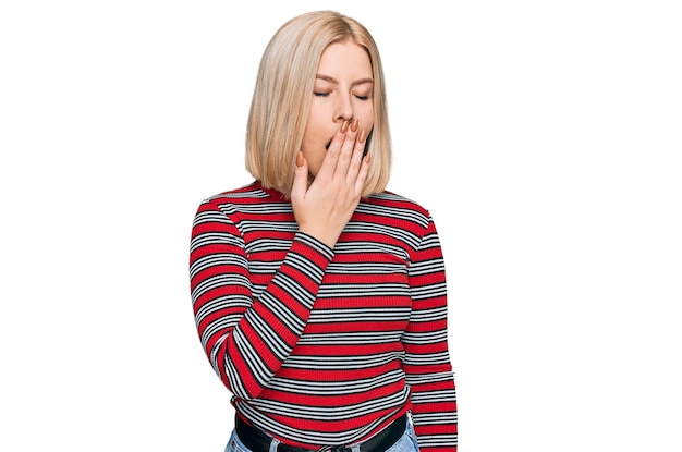 Бесплатное фото Молодая блондинка в обычной одежде скучает зевает устала покрывает рот рукой беспокойна и сонлива