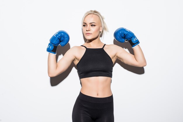 Young blonde woman with blue boxing gloves on white