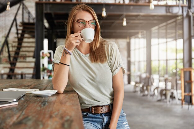 Young blonde woman with glasses in cafe