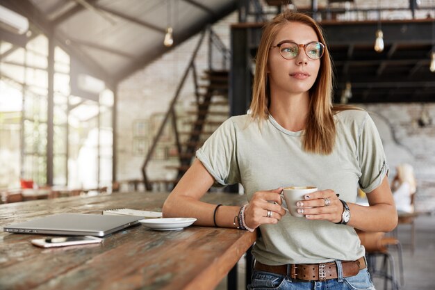 Young blonde woman with glasses in cafe