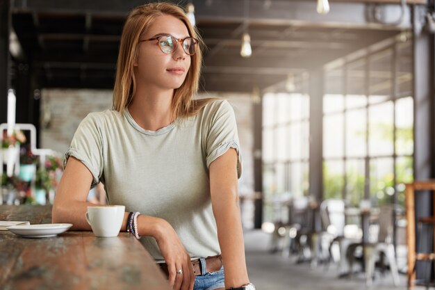 Young blonde woman with glasses in cafe