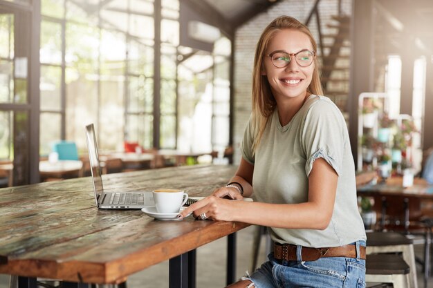 カフェでメガネの若いブロンドの女性