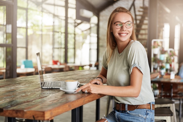 Young blonde woman with glasses in cafe