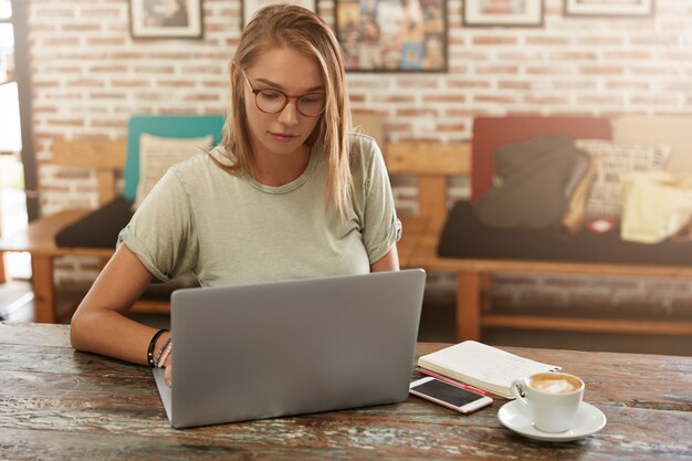 Young blonde woman with glasses in cafe