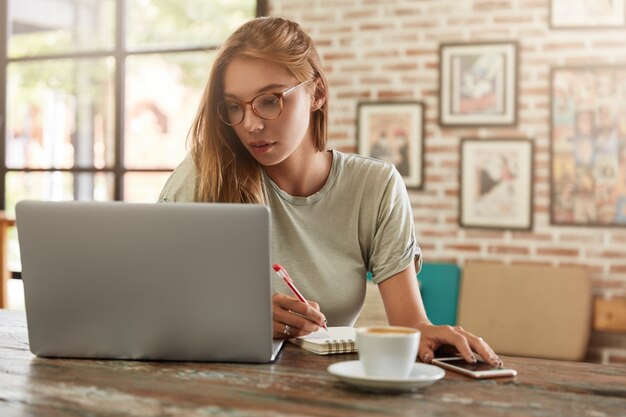 Young blonde woman with glasses in cafe