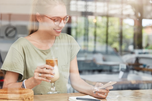 カフェでメガネの若いブロンドの女性