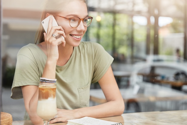 Young blonde woman with glasses in cafe