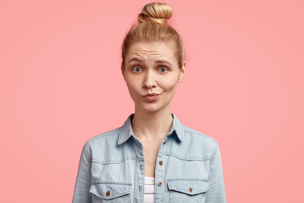 Young blonde woman with hair in bun and wearing denim jacket