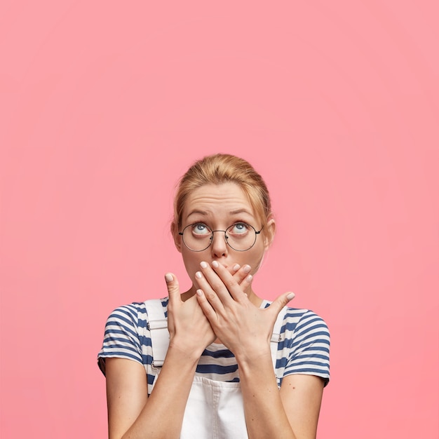 Young blonde woman with round glasses and overalls