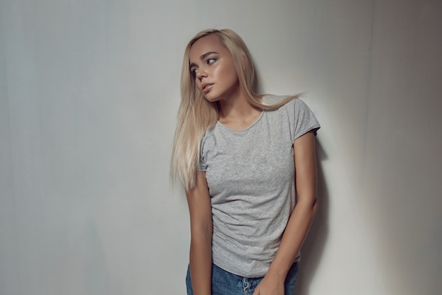 Young blonde woman with shirt on wall