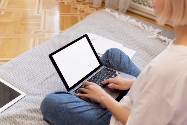 Young blonde woman working from home in her bed