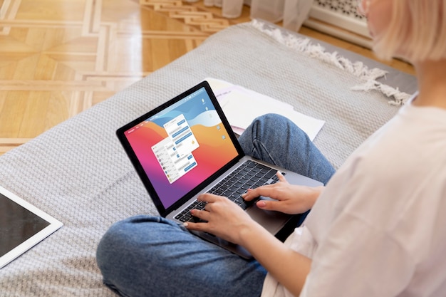 Free photo young blonde woman working from home in her bed