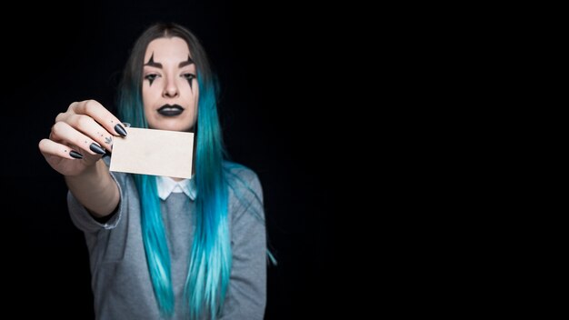 Young blue haired woman holding little paper card