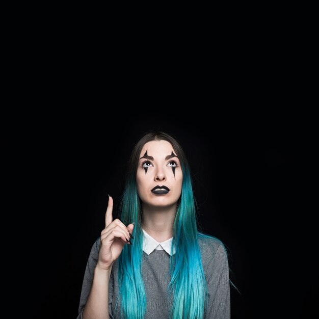 Young blue haired woman pointing with finger up