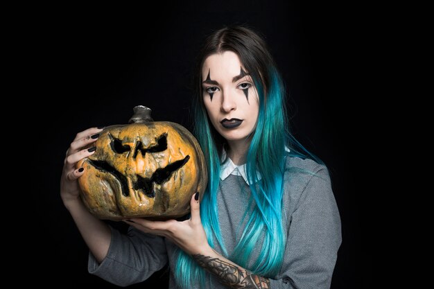 Young blue haired woman posing with pumpkin