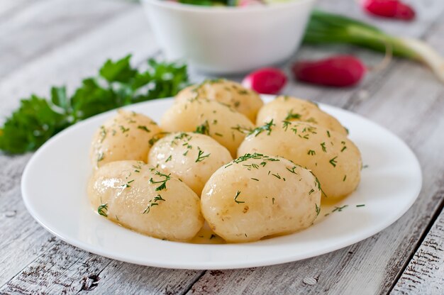 Young boiled potatoes with butter and dill on a white plate