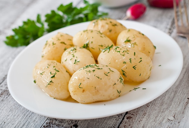 Young boiled potatoes with butter and dill on a white plate